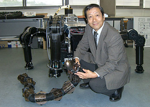 Сигео Хиросе — один из пионеров современной робототехники. Здесь он запечатлён на фоне TITAN-IX, а в руках у него ACM-R5 (разрабатывается с 2005 года) — робот-змея, который умеет и ползать и плавать. Кстати, такие перемещения этот робот осуществляет, в частности, за счёт маленьких колёс, укреплённых на его корпусе (фото с сайта www-robot.mes.titech.ac.jp).